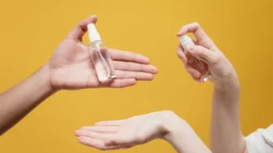 two hands holding bottles of Sanitizer